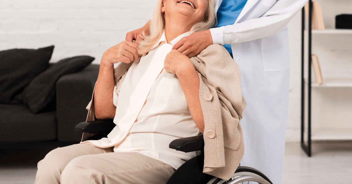 Elderly woman smiling in a wheelchair while being cared for