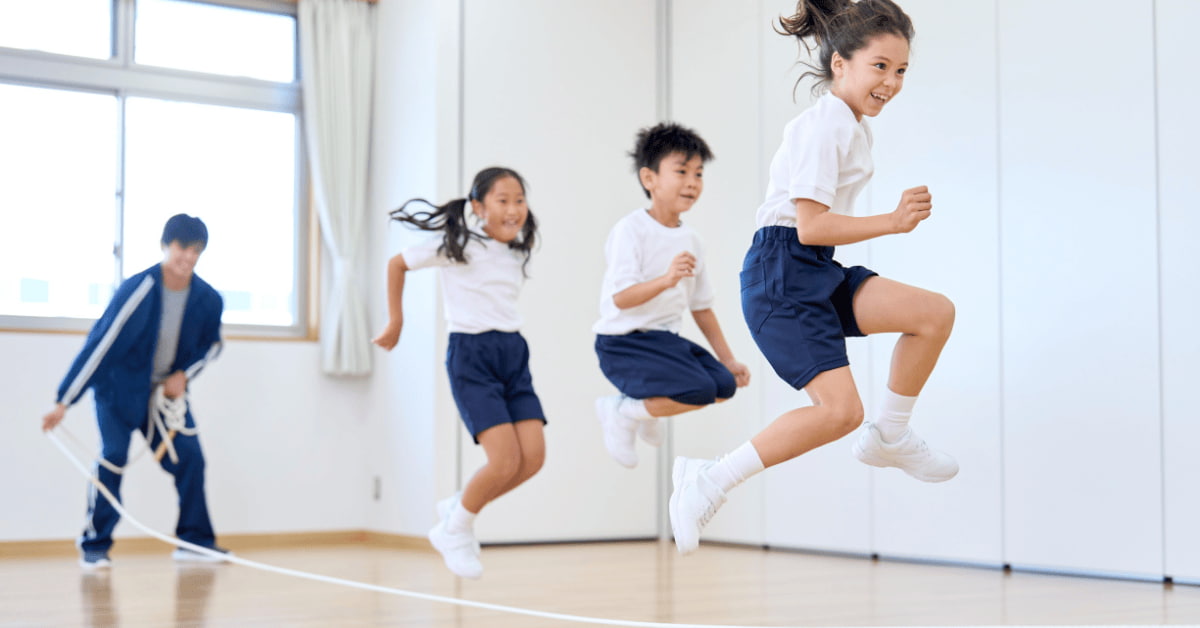 Children playing and jumping in a school gym, highlighting the importance of safe physical activity for kids who may experience seizures.
