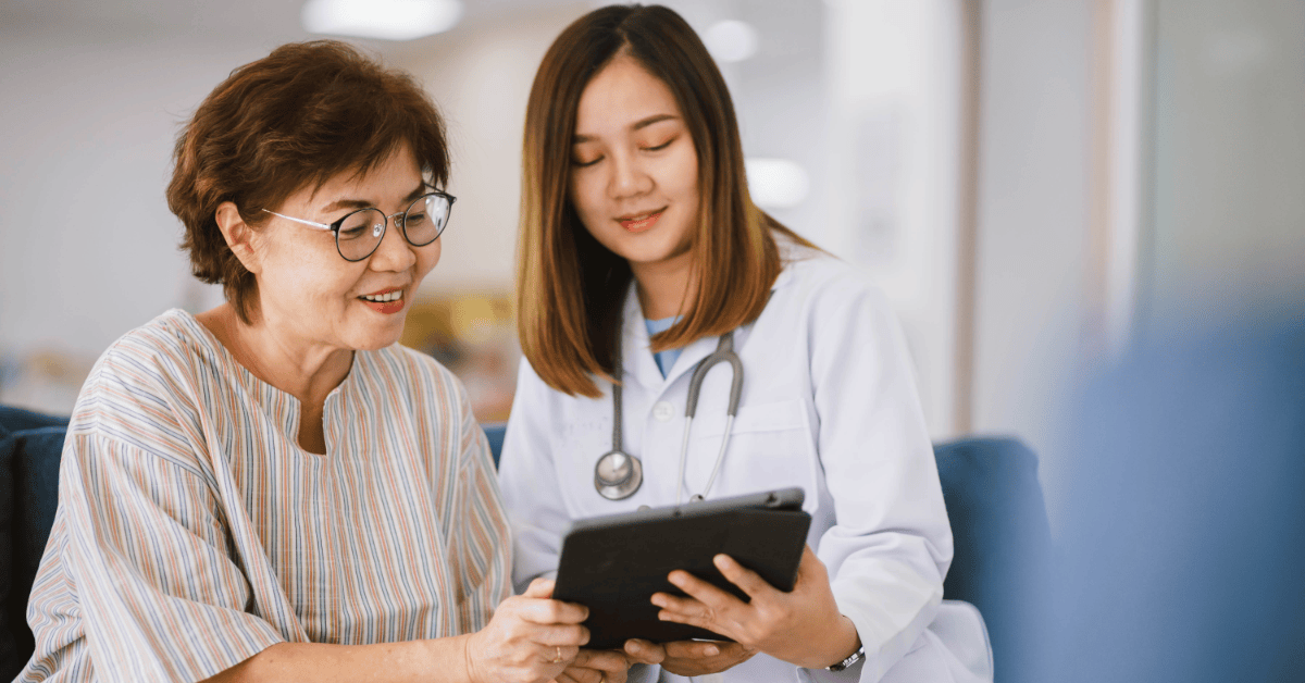 Doctor assisting a patient while using an app for diabetes on a tablet to review blood sugar and health data.
