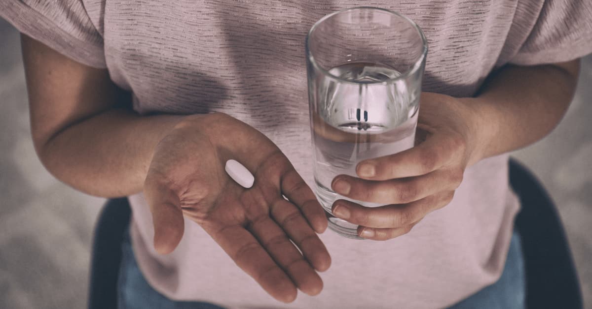 Person holding medication and water as part of schizophrenia treatment
